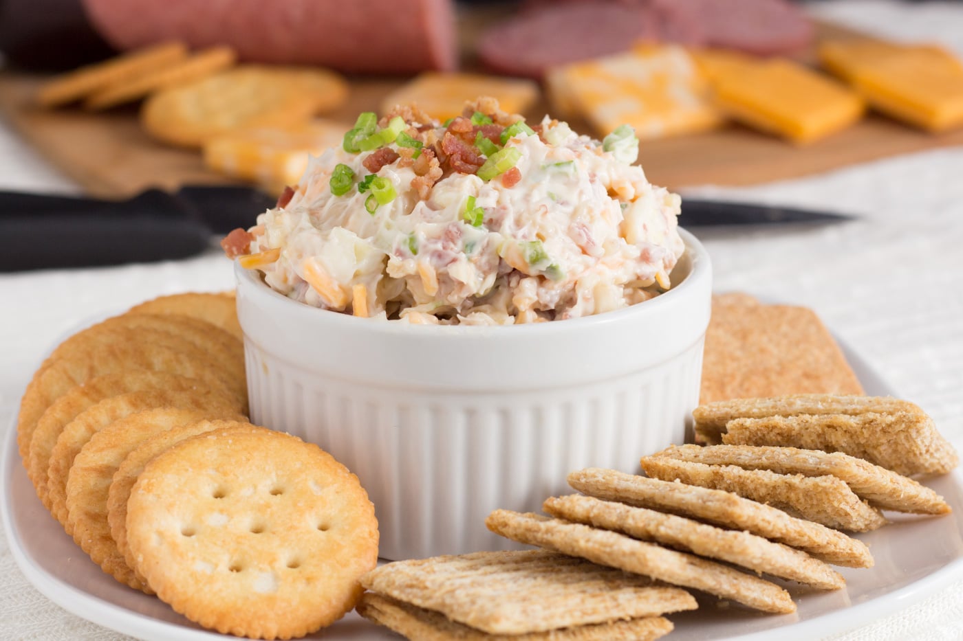 Bacon and mayonnaise dip in a crock surrounded by crackers