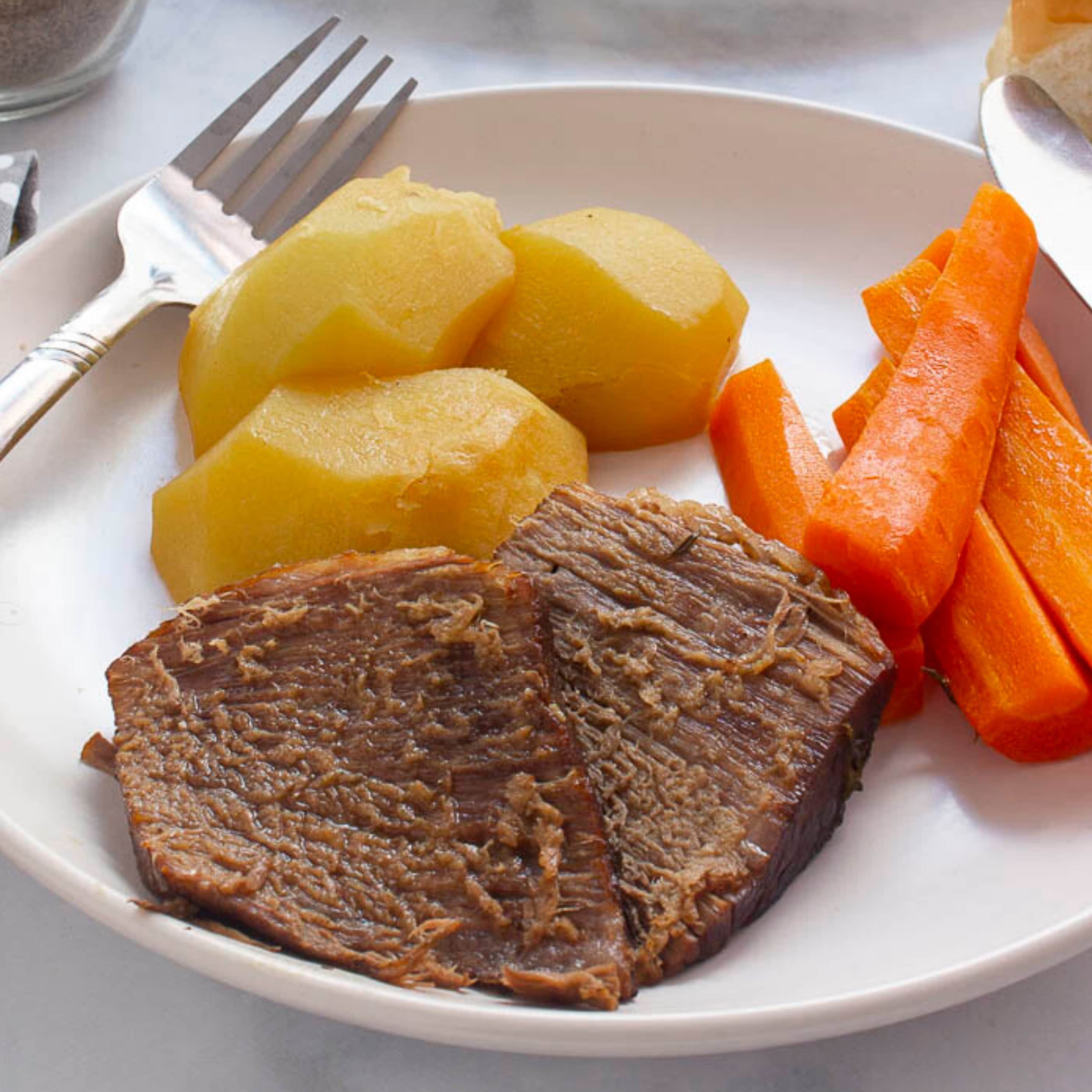Pot Roast with vegetables on a plate with a fork and knife