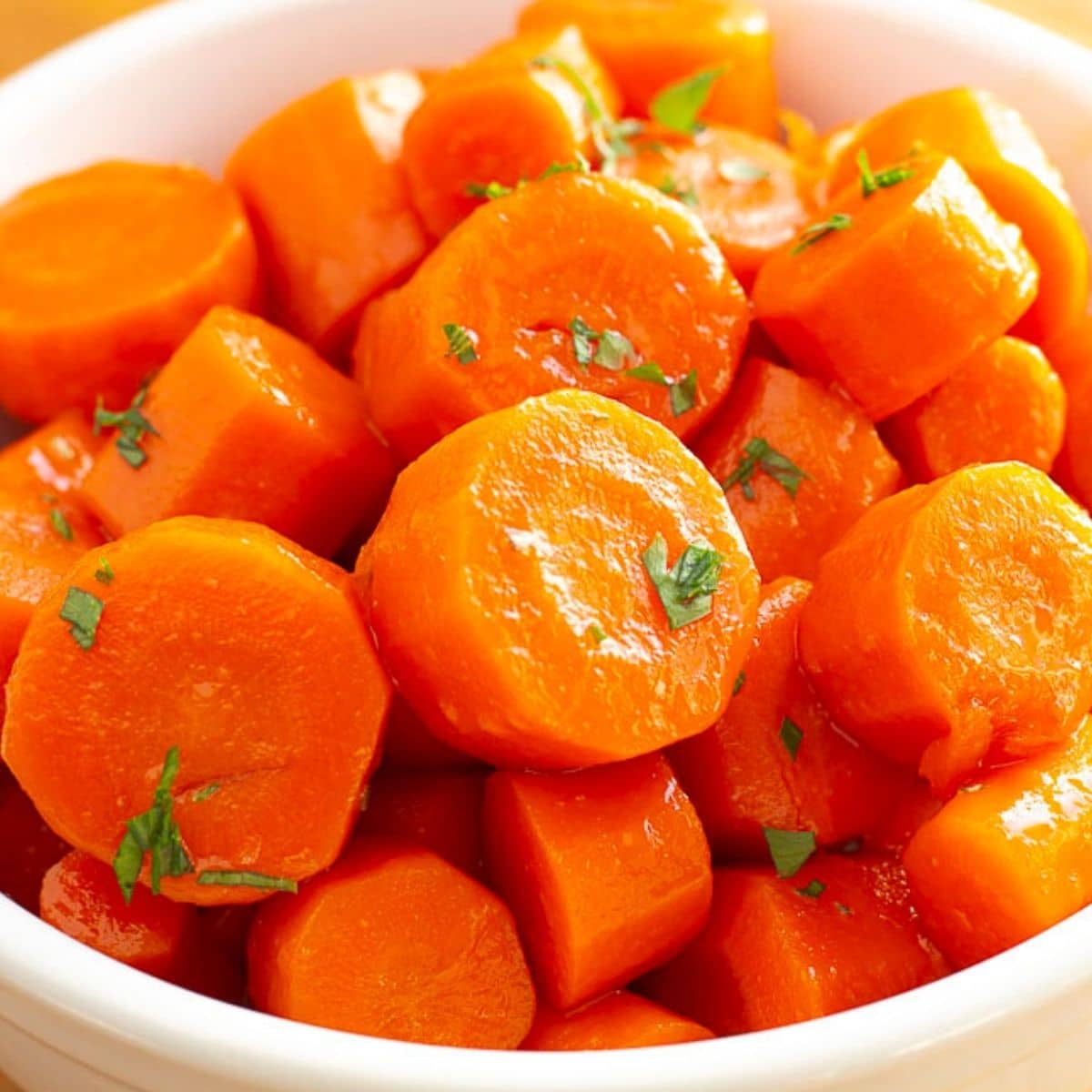 Candied carrots topped with parsley in a white bowl