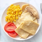 Overhead view of chicken and dumplings with corn and tomatoes