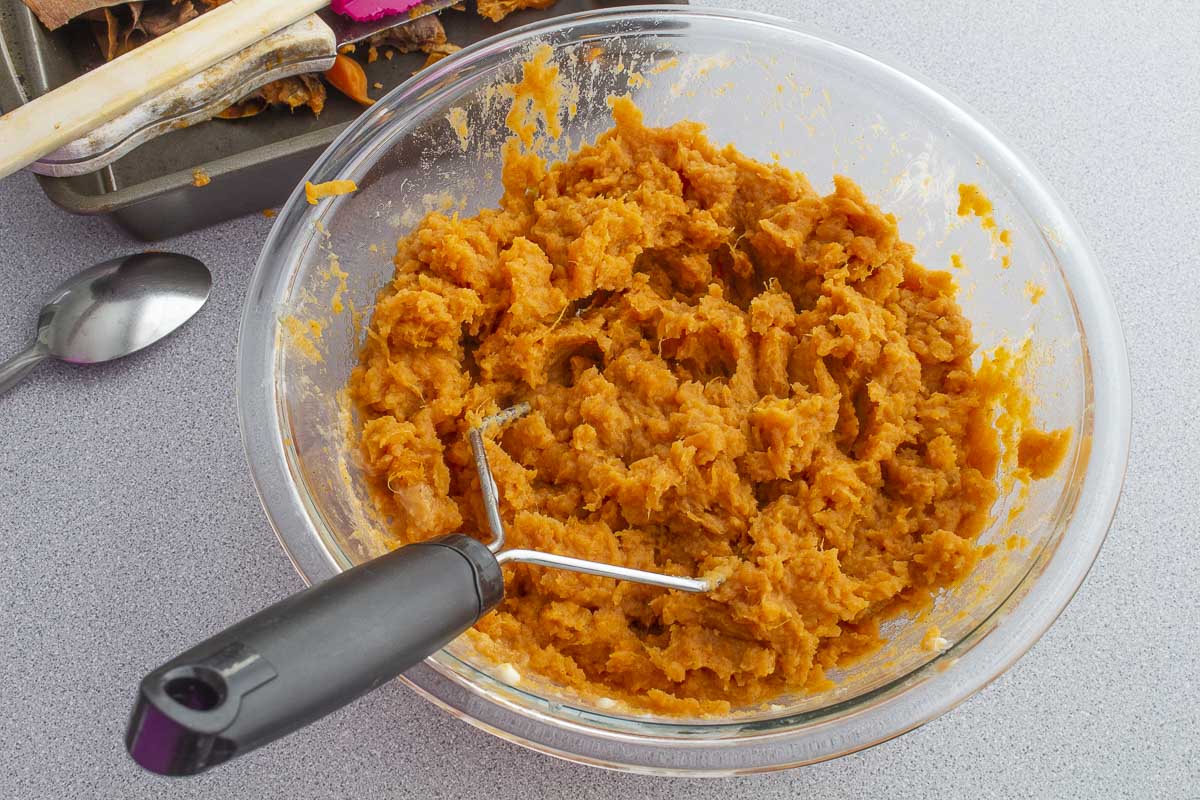 smashin sweet potatoes in a glass bowl