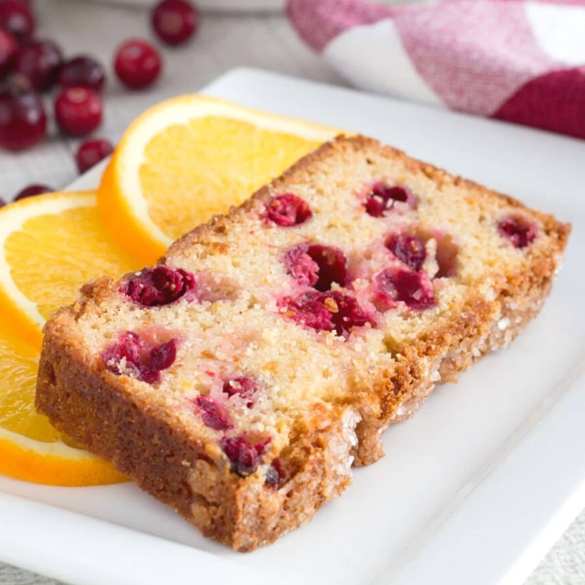 Slice of cranberry bread on a plate with orange slices