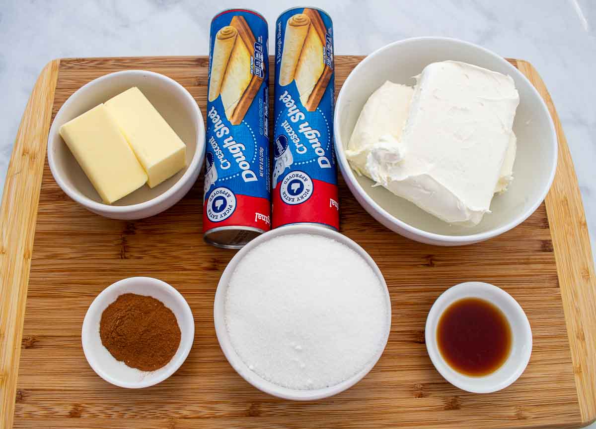 Butter, crescent roll dough, cream cheese, cinnamon, sugar, and vanilla on a wooden board
