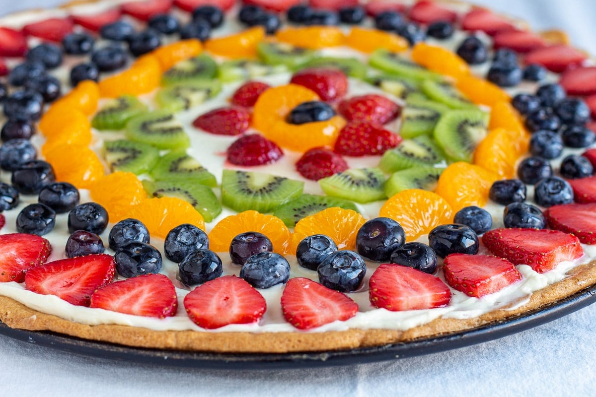 sugar cookie pizza topped with cream cheese and fruit