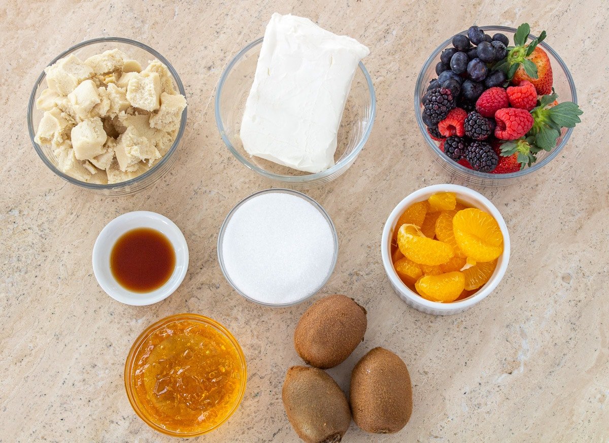 Cookie dough, cream cheese, mixed fruit, vanilla, sugar, mandarin oranges, apple jelly, and kiwi in bowls