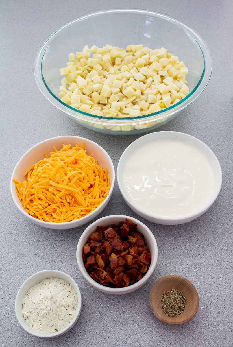 diced potatoes, cheddar cheese, sour cream, bacon bits, ranch dressing and black pepper in bowls