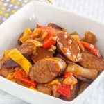 Italian sausage slices in a bowl with peppers and onions