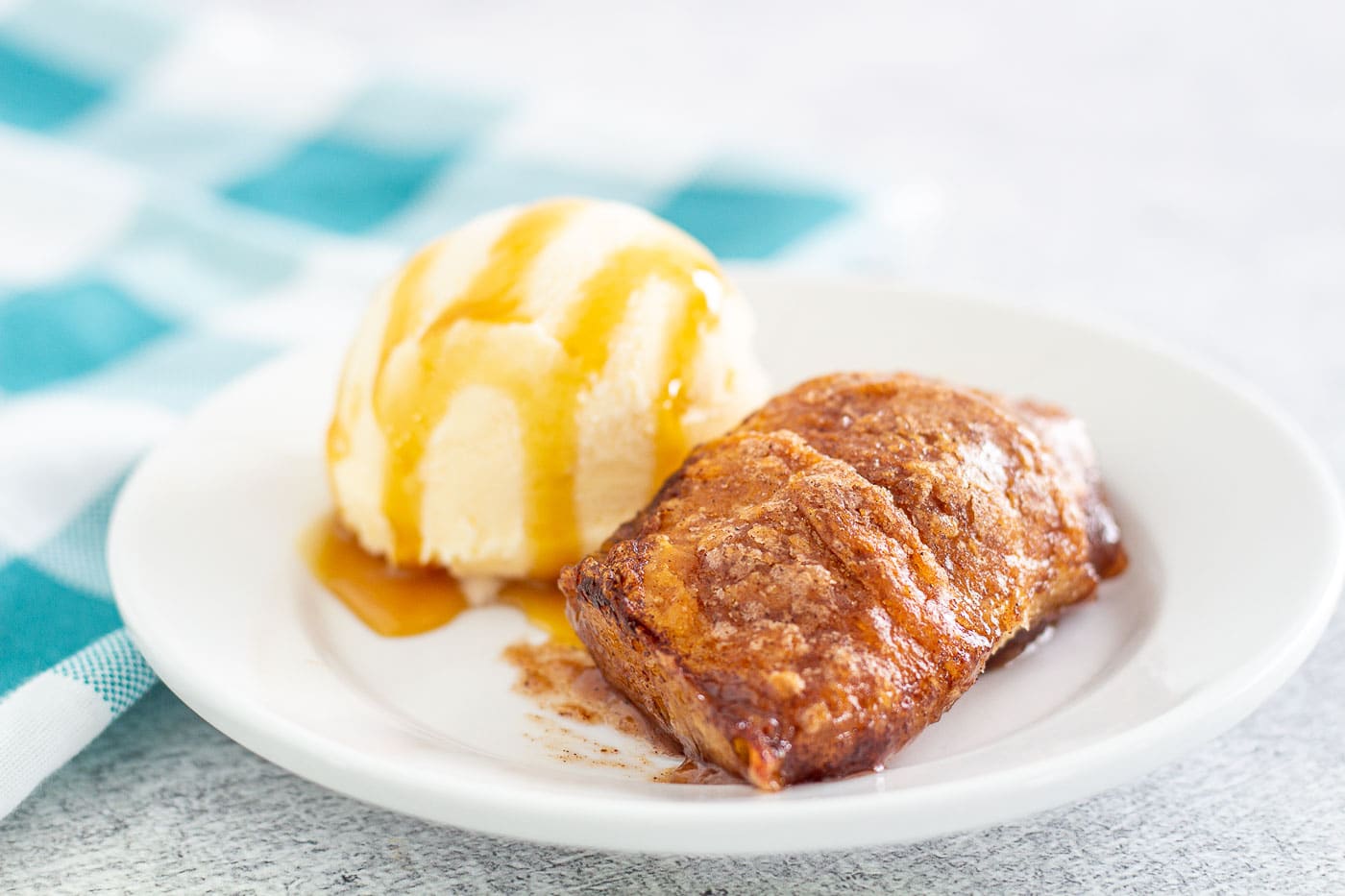 Apple dumpling with ice cream and caramel sauce on a white plate