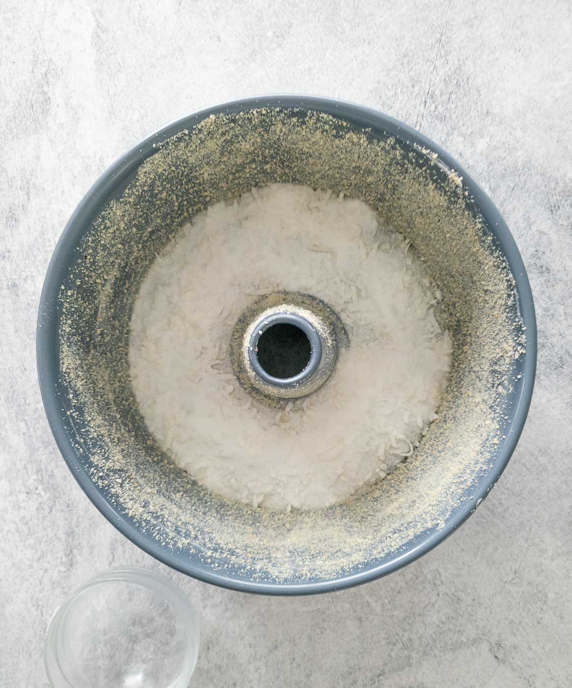 Granulated sugar and coconut mixture spread into the bottom of a tube pan.