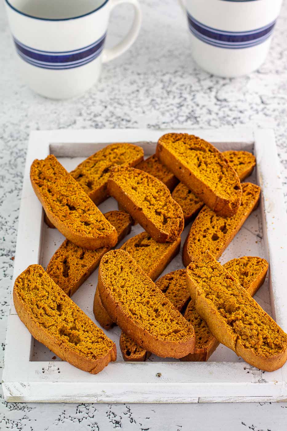 Cookies in a wooden tray with coffee cups in the back