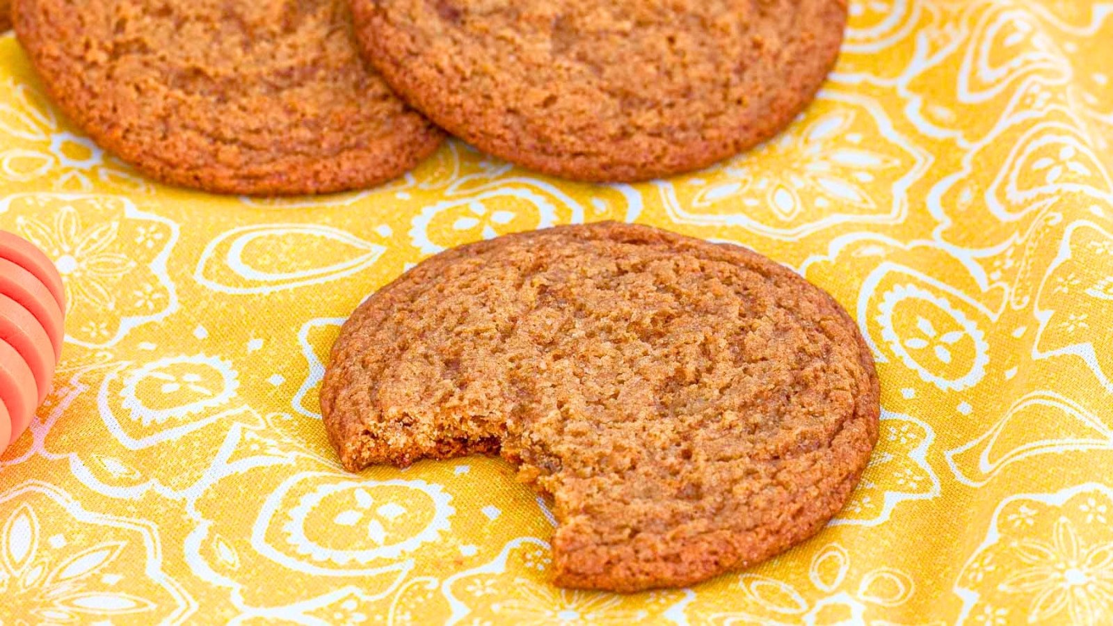 Honey cookie missing a bite sitting on a napkin in front of more cookies