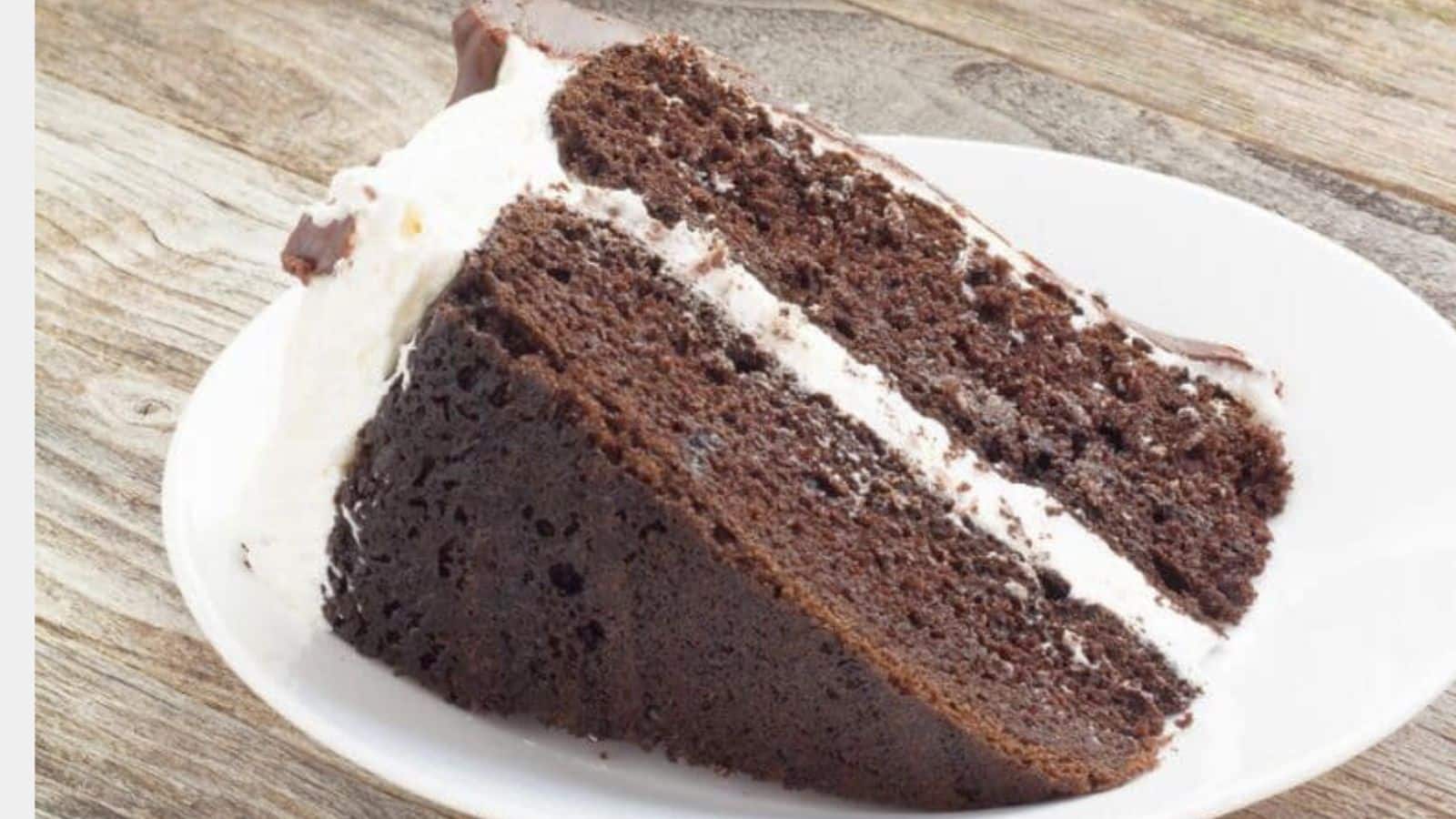 Chocolate cake slice with white frosting on a plate