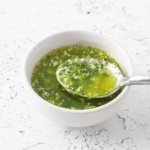 garlic butter sauce with parsley in a bowl with a spoon