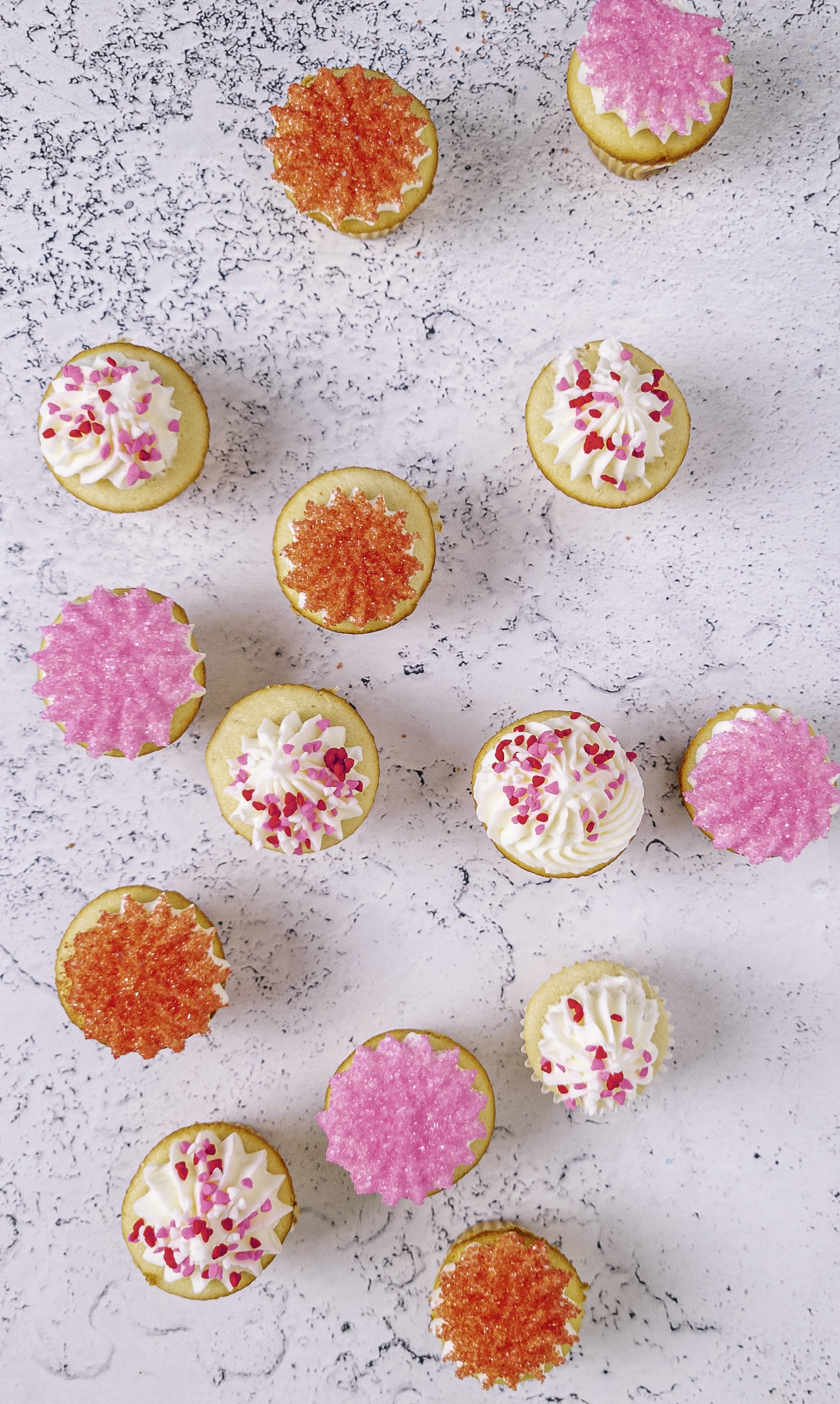 Overhead view of pink, red, and white mini cupcakes decorated with sprinkles
