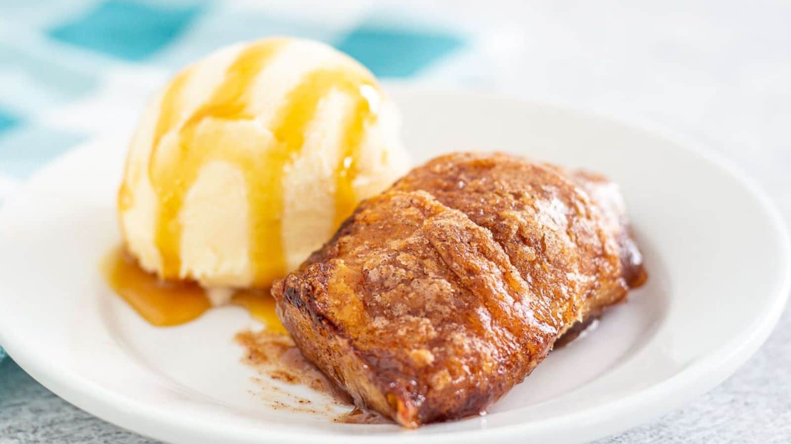 Apple dumpling and ice cream on a plate drizzled with caramel sauce
