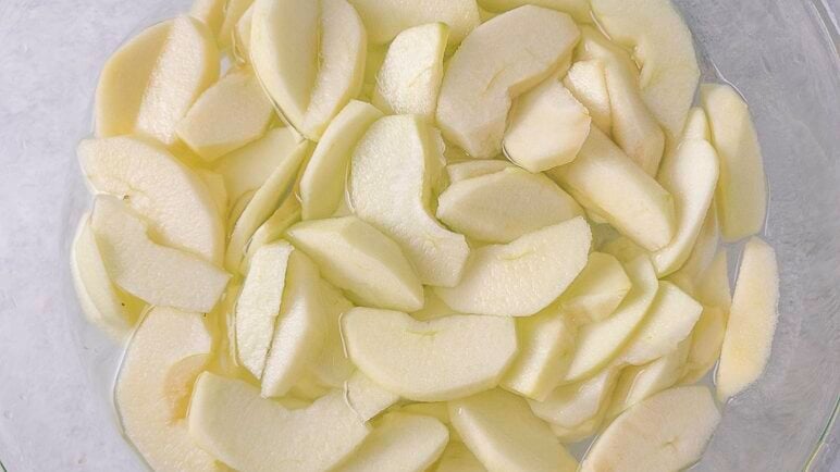 Apple slices in a bowl of water with lemon juice