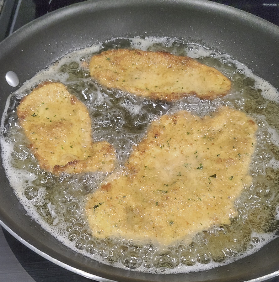 breaded chicken cutlets frying in a skiller