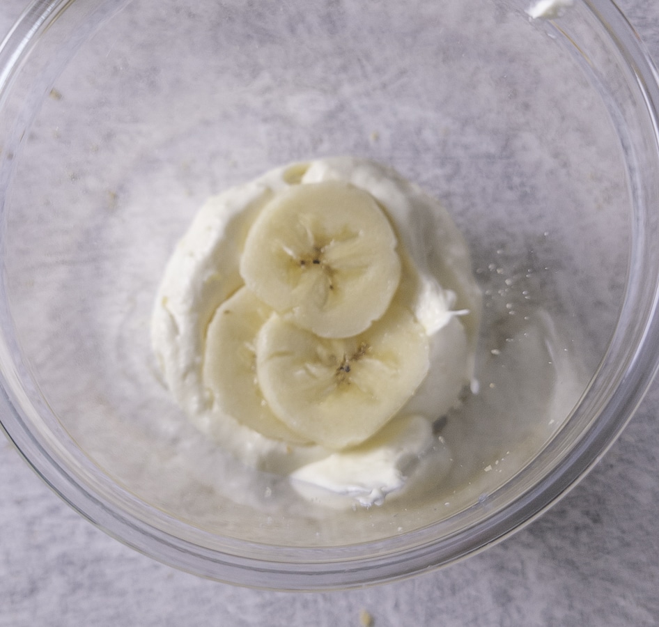 banana slices on top of pudding in a plastic dessert cup