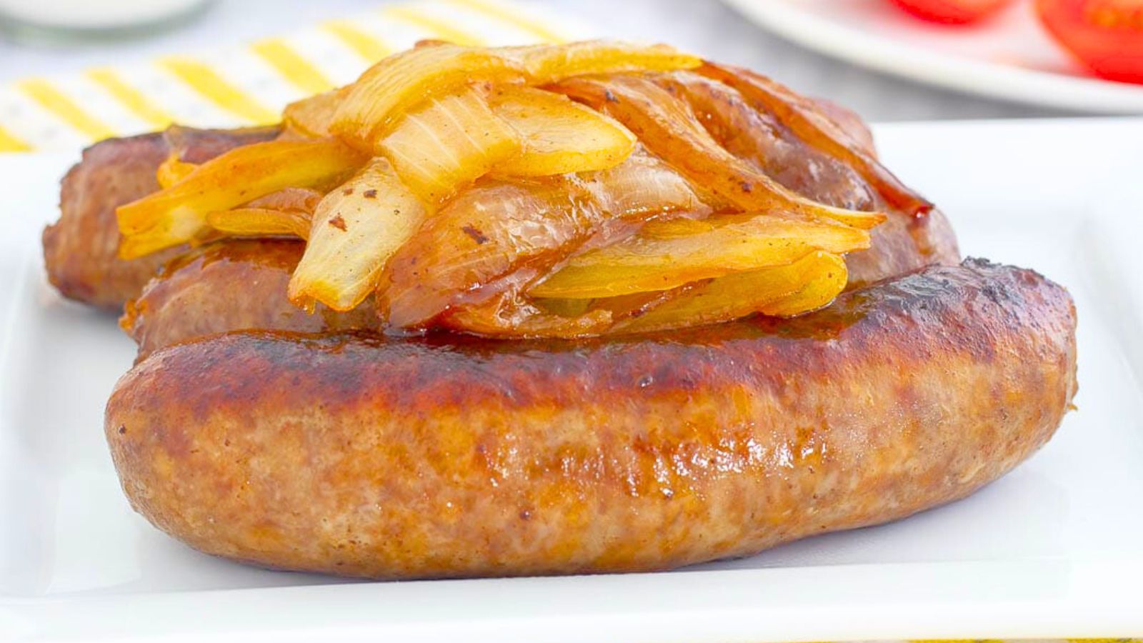 Bratwurst topped with braised onions on a plate