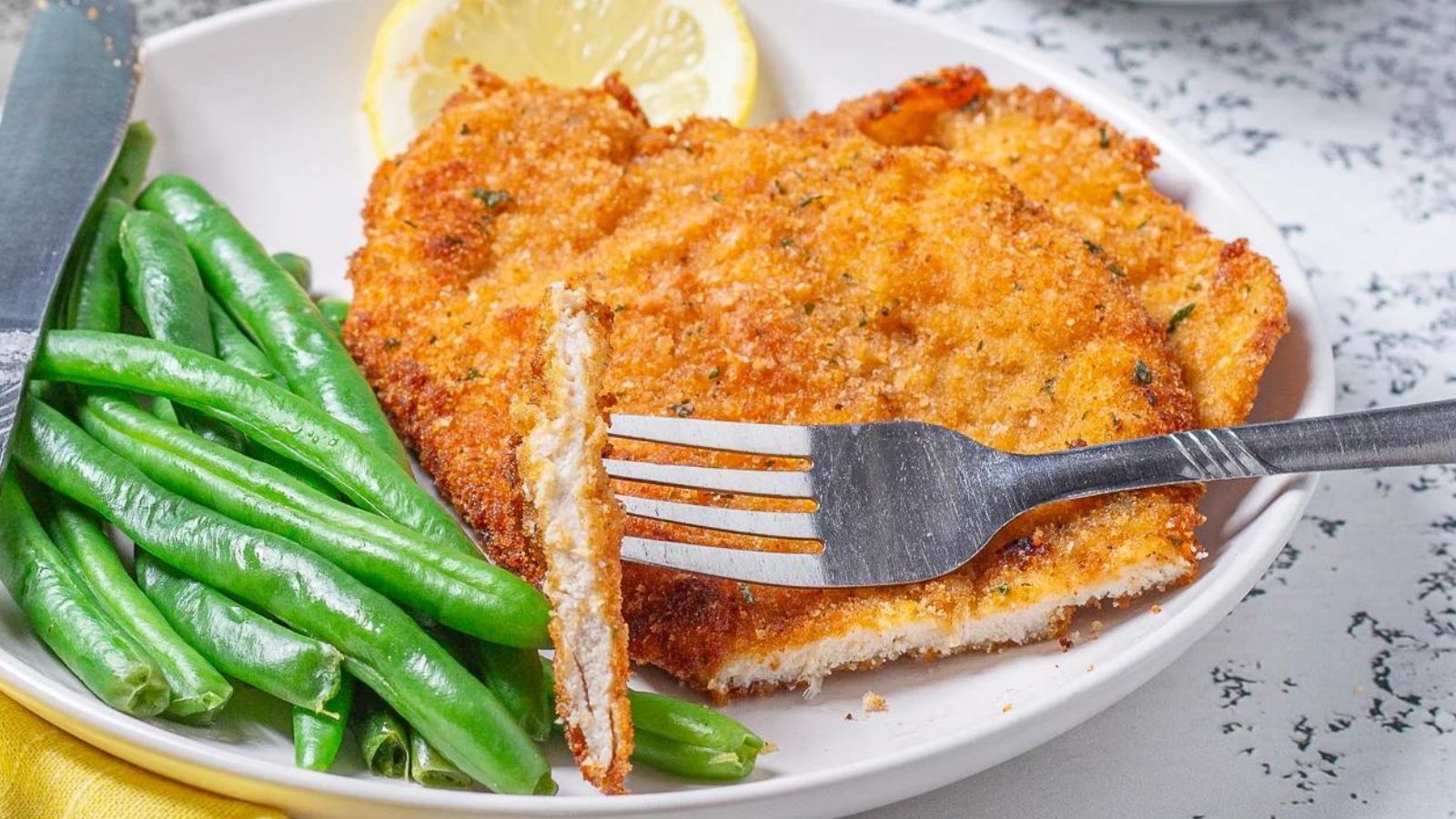 Fried chicken cutlet and green beans on a plate