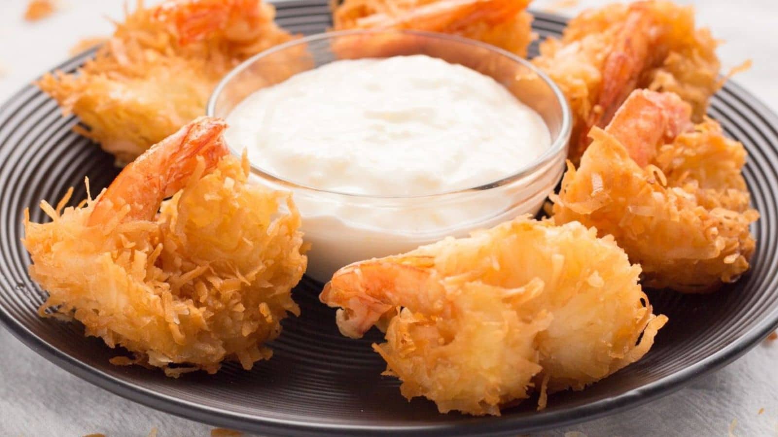 Coconut Shrimp on a black plate with pina colada sauce