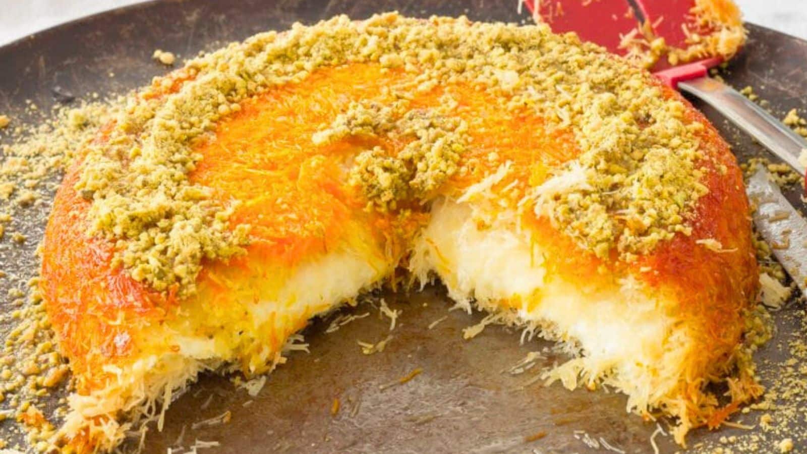 Knafeh topped with crushed pistachios with slices missing