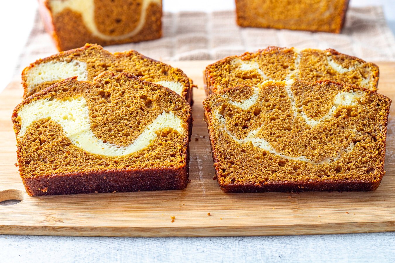 slice of pumpkin swirl bread on a cutting board the one on the left has 2 layer of swirl the slice on the right has 2 swirl layers