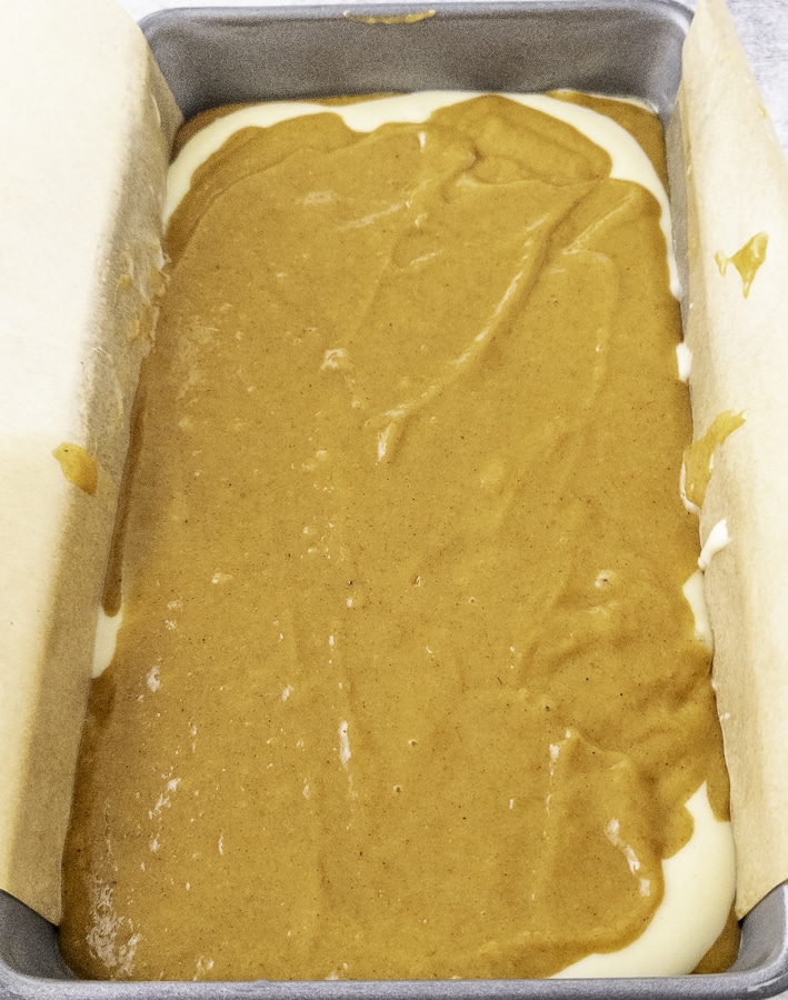 layers of pumpkin batter and cheese cake batter in a pan