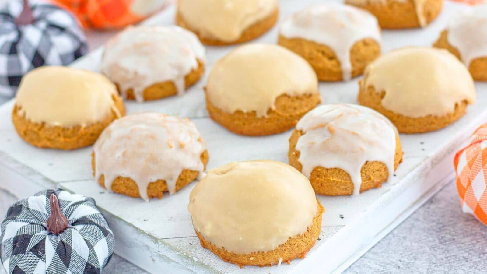 Iced pumpkin cookies on a white background with decorative pumpkins