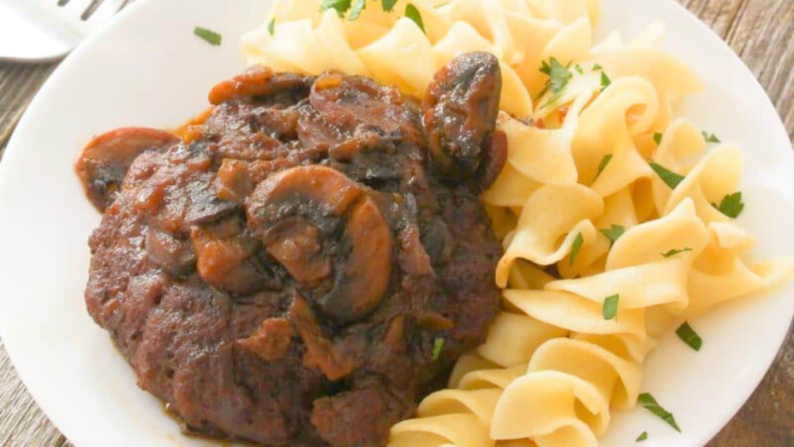 Salisbury steak with mushrooms on a plate with noodles