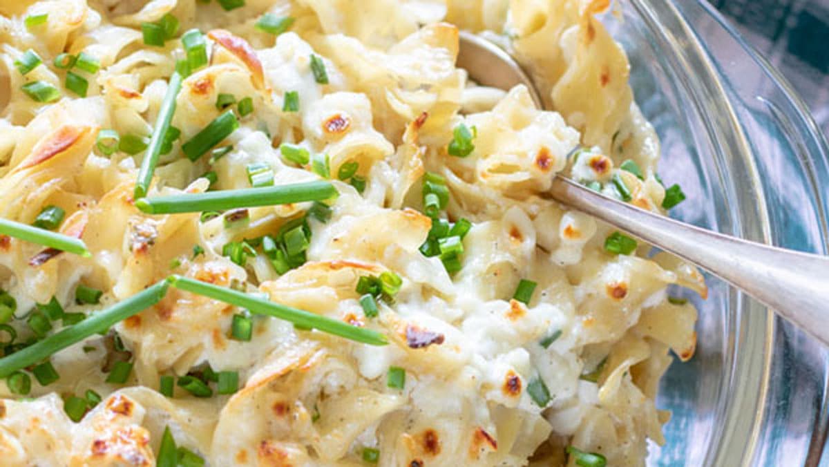 Cheesy casserole topped with green onions with a spoon in it