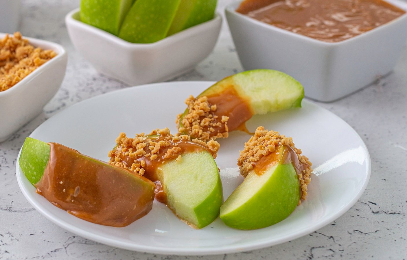Apple slices coated with caramel and peanuts