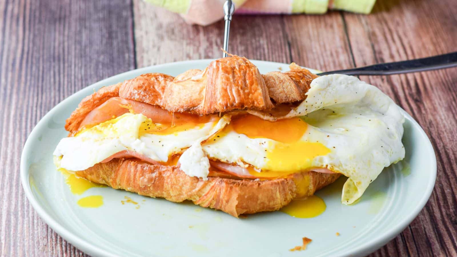 ham cheese and egg on a croissant with a fork