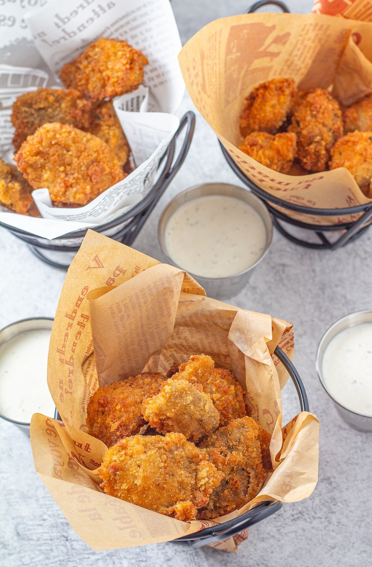 Fried mushrooms in a basket with cups of ranch dressing