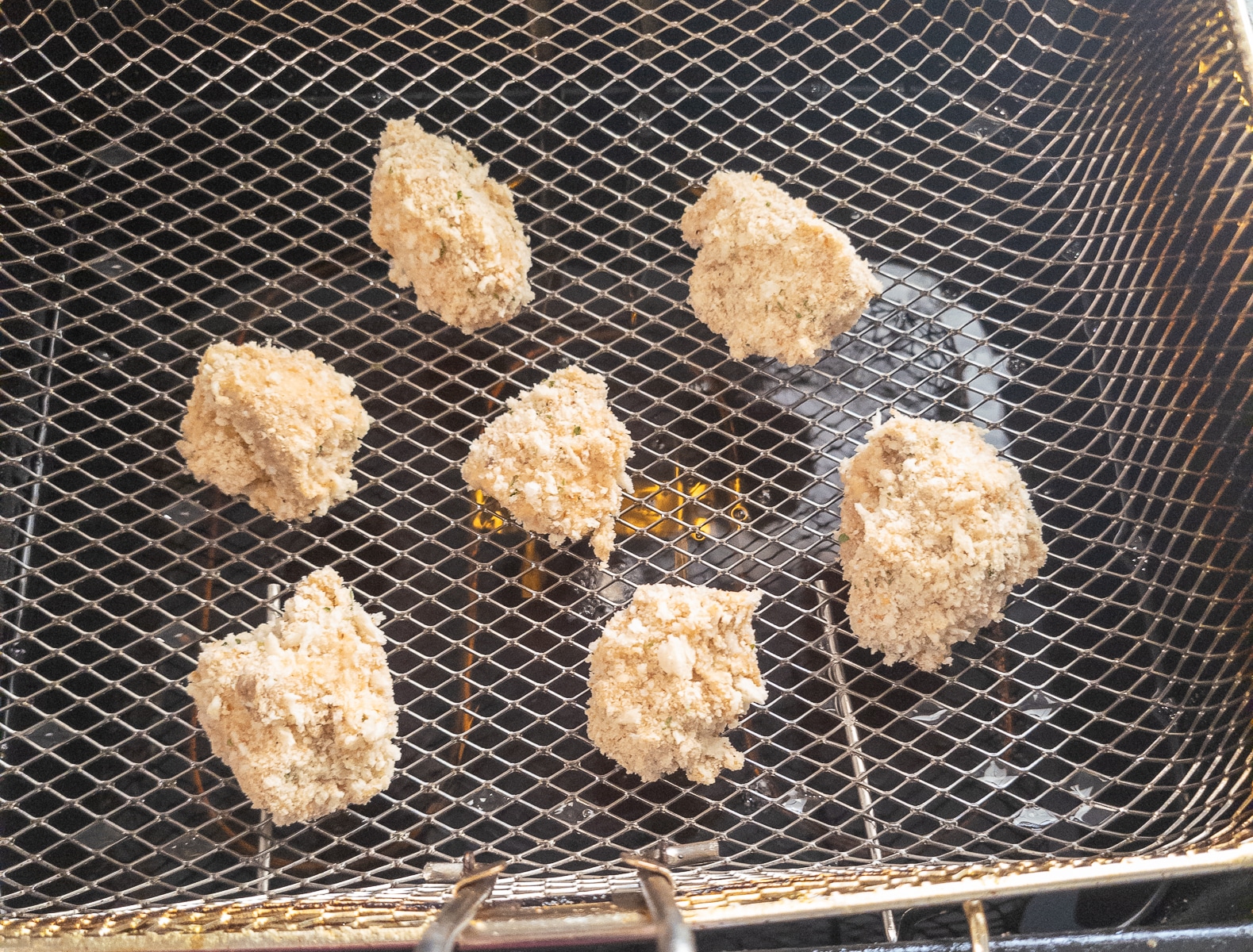 Battered mushrooms in a frying basket.