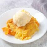 Peach cobbler topped with ice cream on a plate