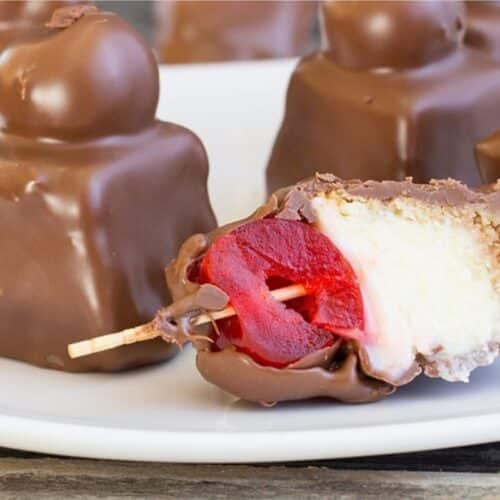 Cheesecake bites covered in chocolate with a cherry