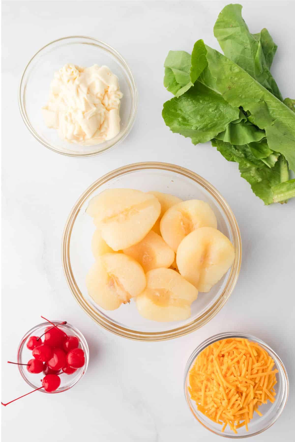 mayonnaise lettuce pear halves cherries and cheese in bowls
