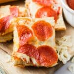 Pieces of French bread pizza surrounded by shredded cheese