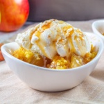 apple dump cake topped with ice cream and caramel sauce in a bowl