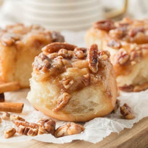 Sticky rolls topped with pecans on a board