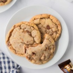 toffee cookies on a plate with a bite missing on the top one