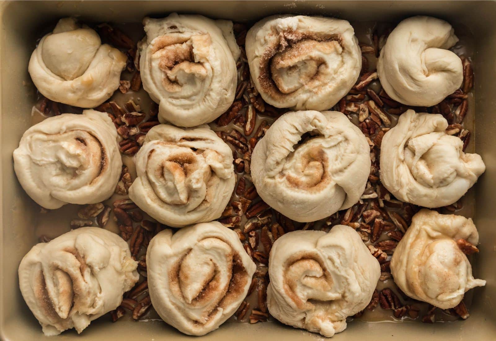 Cinnamon rolls on top of pecan caramel topping in a pan