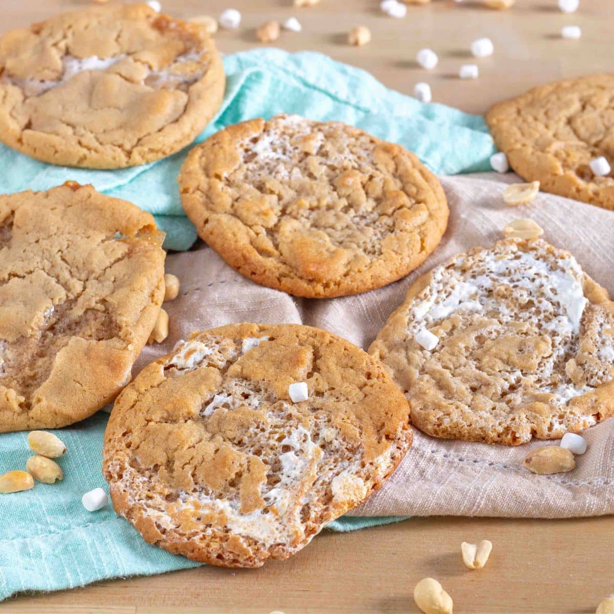Fluffernutter Cookies on teal and beige napkins surrounded by peanuts and dried marshmallows