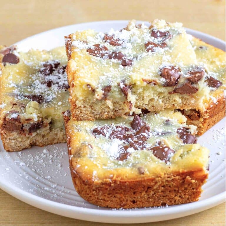 slices of gooey butter cake with chocolate chips stacked on a white plate