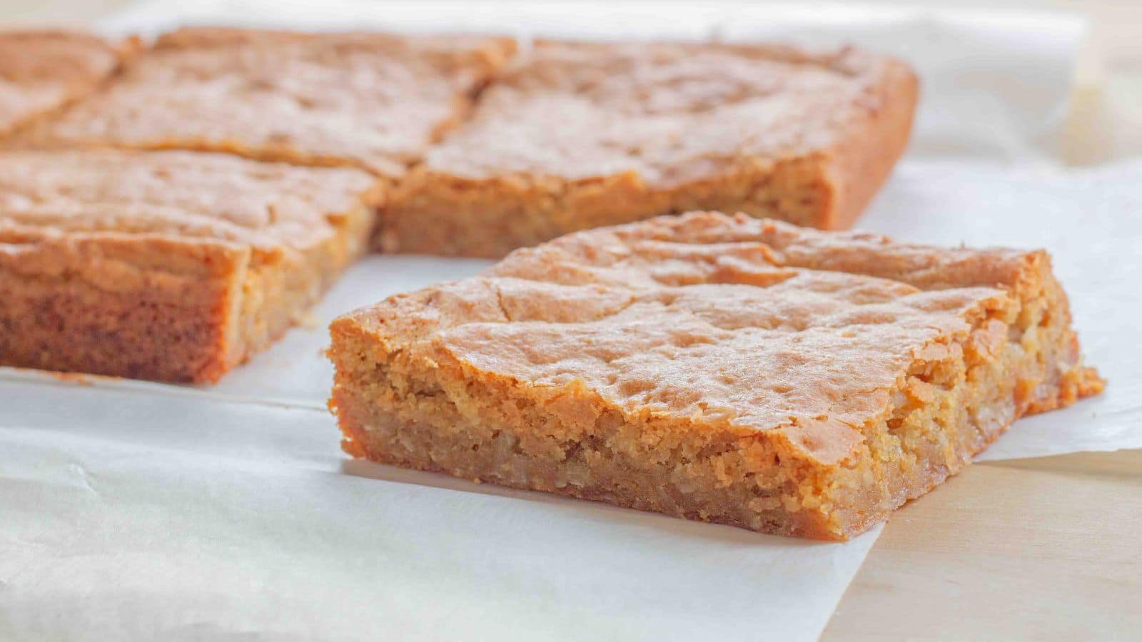 blondies being cut sitting on parchment paper