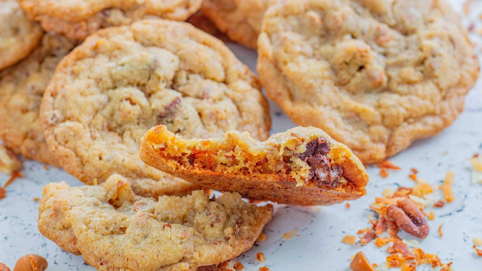 cookie with coconut chocolate chips cinnamon chips and nuts broken in half with cookies int eh background