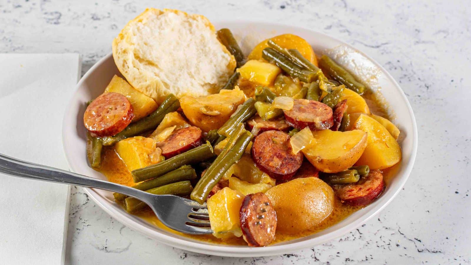 swamp potatoes on a plate with a fork and biscuit half