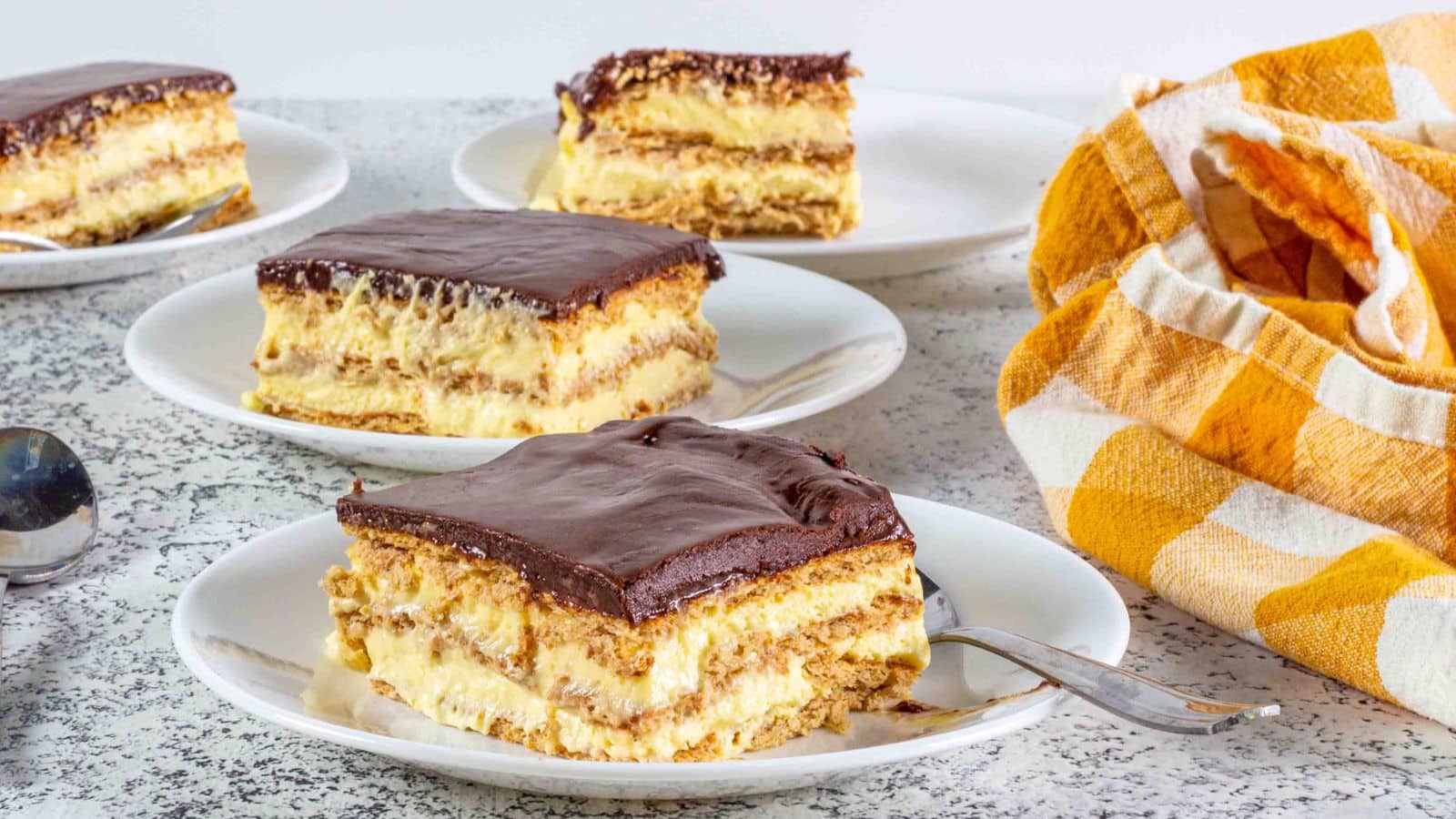 eclair cake slices on plates next to a yellow buffalo check napkin