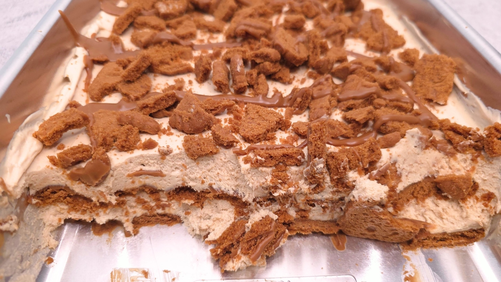 Biscoff lasagna in a pan with scoops removed